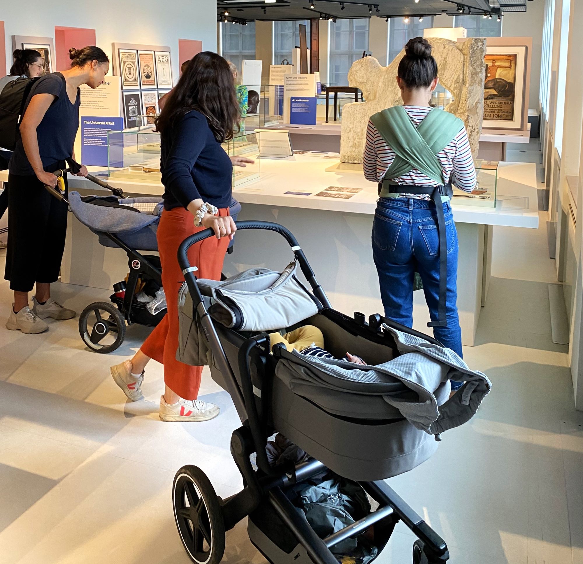 Frauen mit Kinderwagen und Baby in der Ausstellung